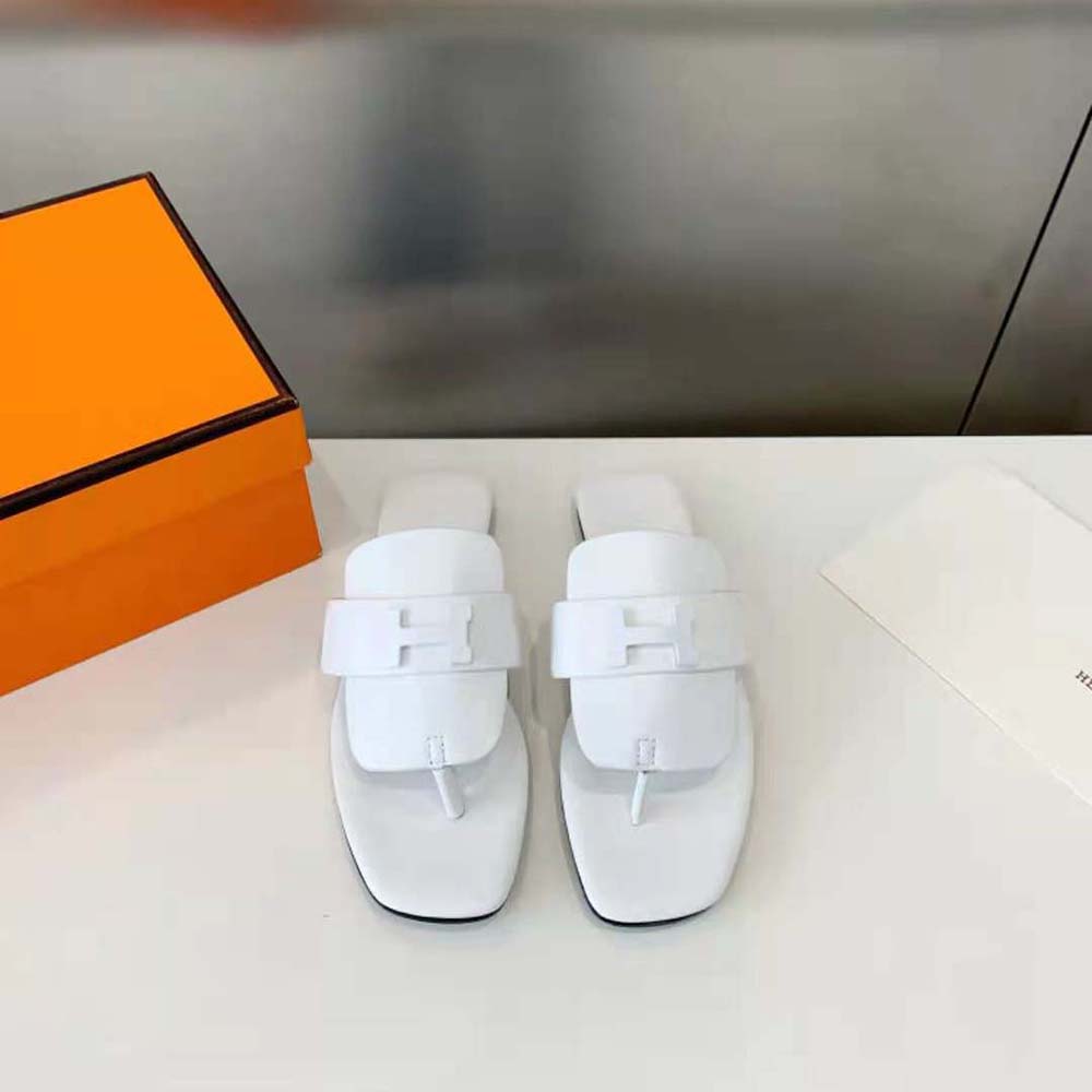 Close-up of white calfskin and signature hardware on Hermes sandal