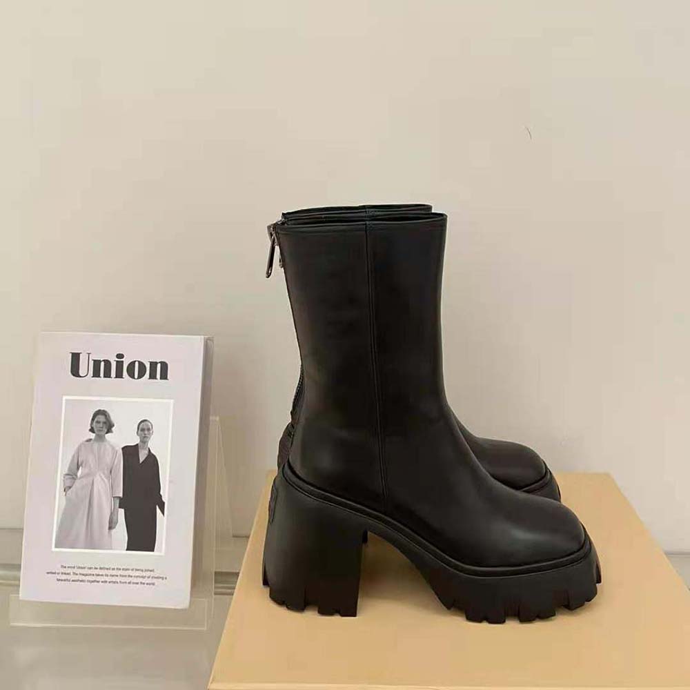 Close-up on embossed Miu Miu logo on black leather booties