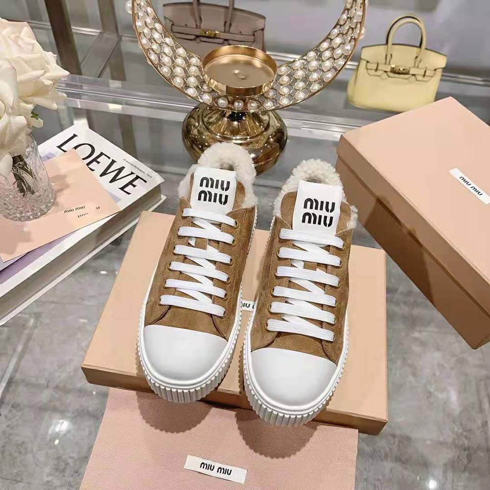 Close-up of beige suede texture and Miu Miu logo on sneakers