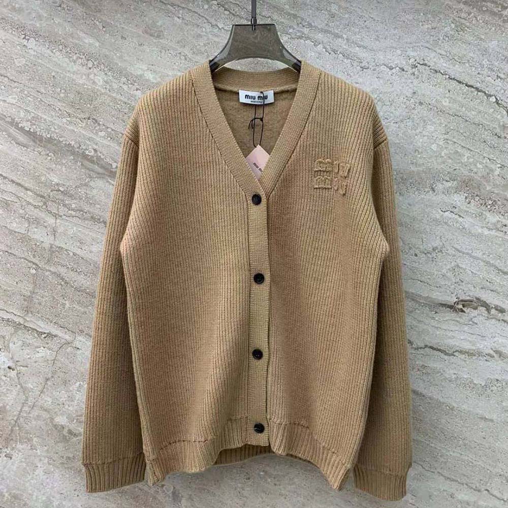 Close-up detail of beige knit fabric and Miu Miu buttons on cardigan