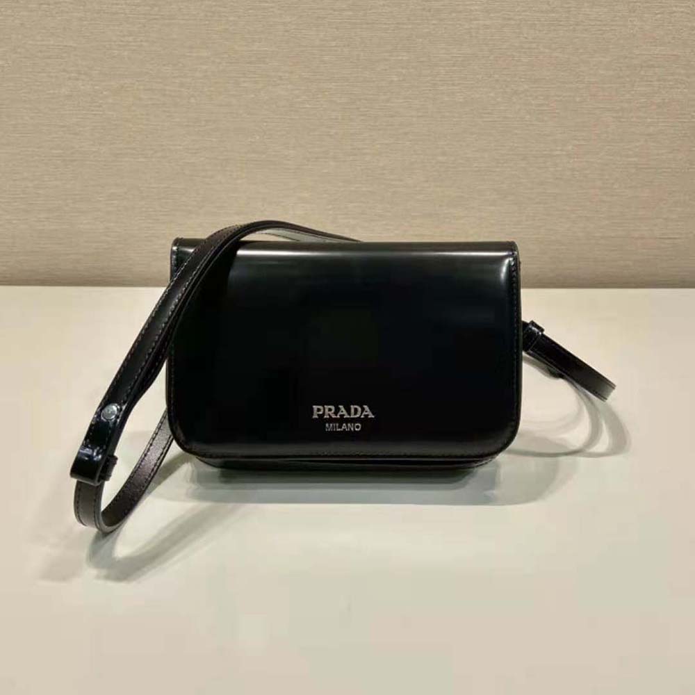 Close-up of Prada triangle logo on black leather mini-bag