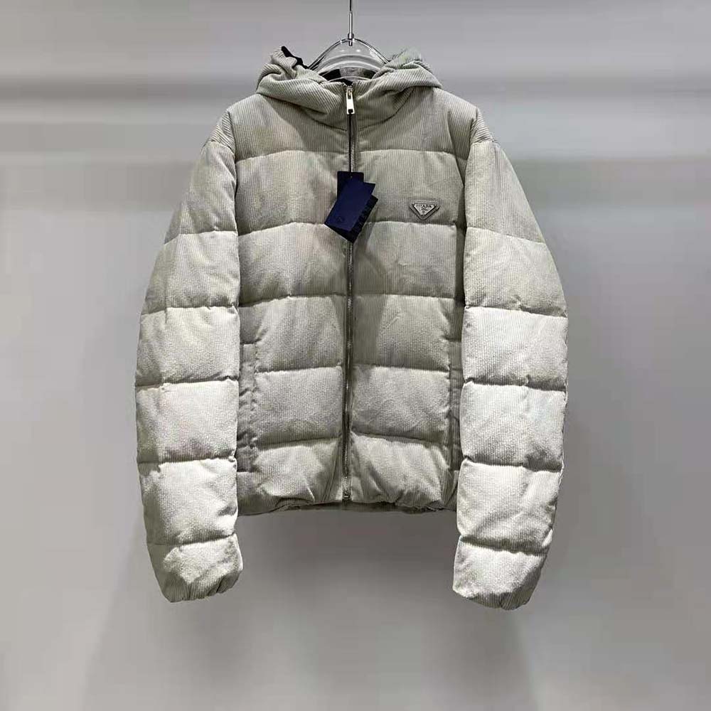 Close-up of silver Prada logo hardware on white corduroy jacket
