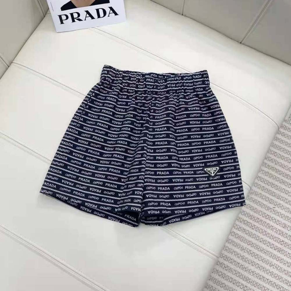 Close-up of Prada logo hardware on the blue nylon shorts