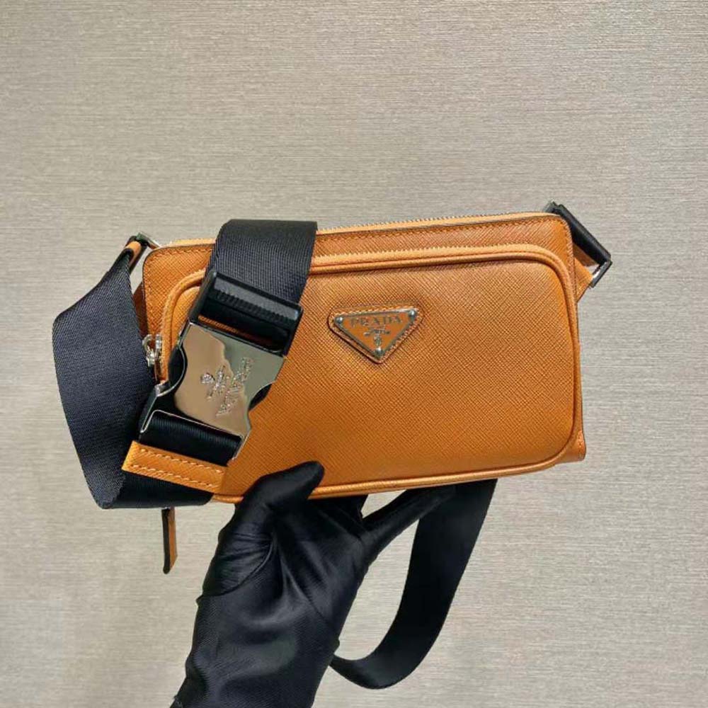 Close-up of silver Prada logo on orange leather belt bag