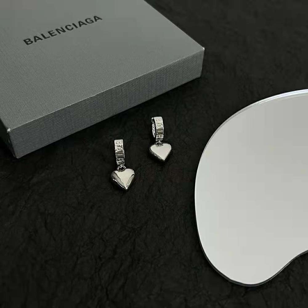 Styling shot of Balenciaga Women Sharp Heart Earrings worn with elegant outfit