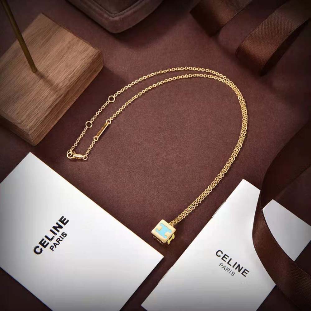 Flat lay of Celine Women Triomphe Cube Necklace showing gold finish and enamel
