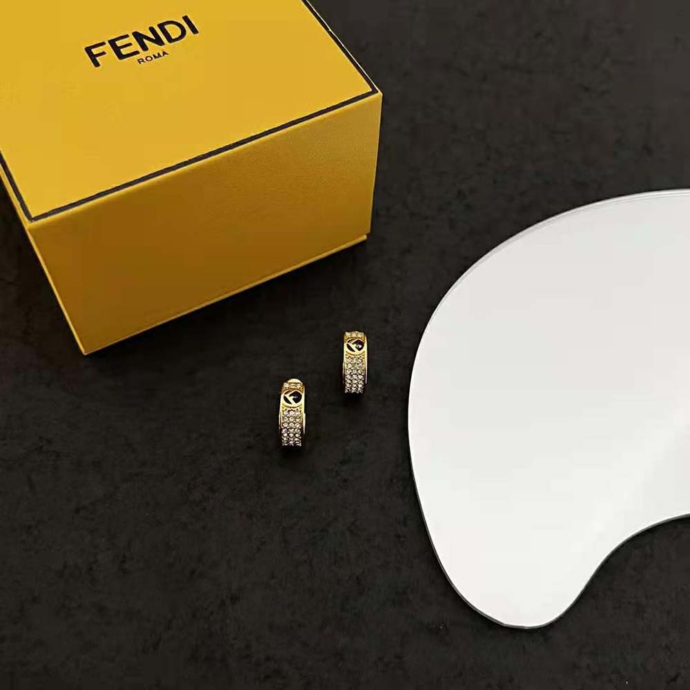 Close-up detail of F is Fendi motif on gold-coloured small hoop earrings