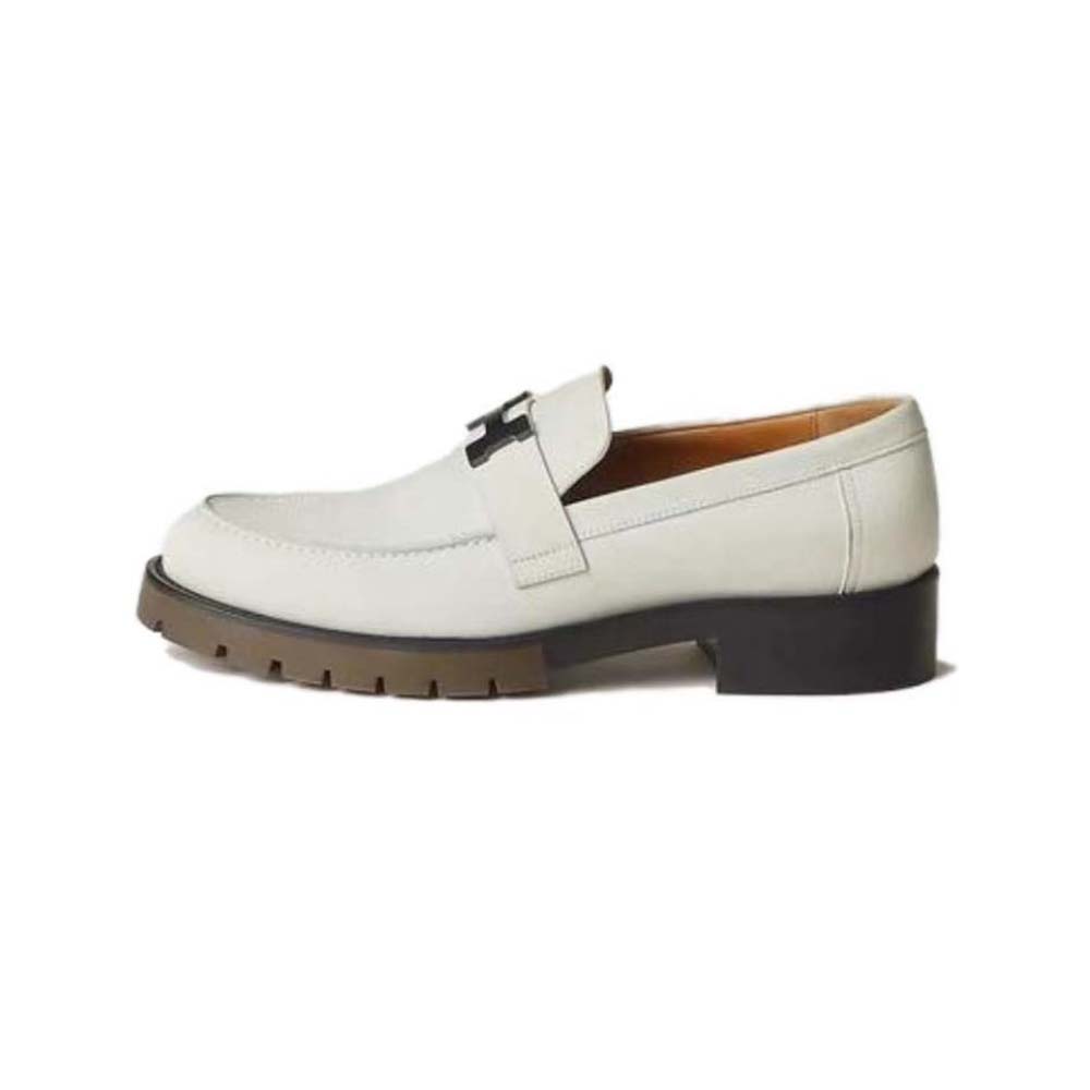 Close-up on silver Hermes hardware detail on white nubuck loafer