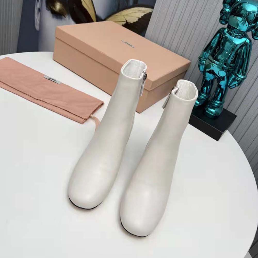 Close-up of metal lettering logo detail on Miu Miu white booties