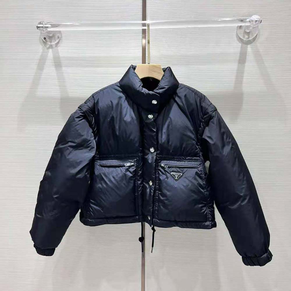 Close-up on Prada logo plaque on black cropped Re-Nylon down jacket