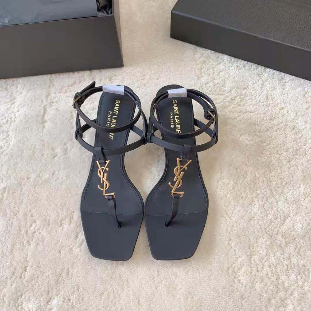 Close-up of gold YSL logo hardware on Cassandra Sandals black leather