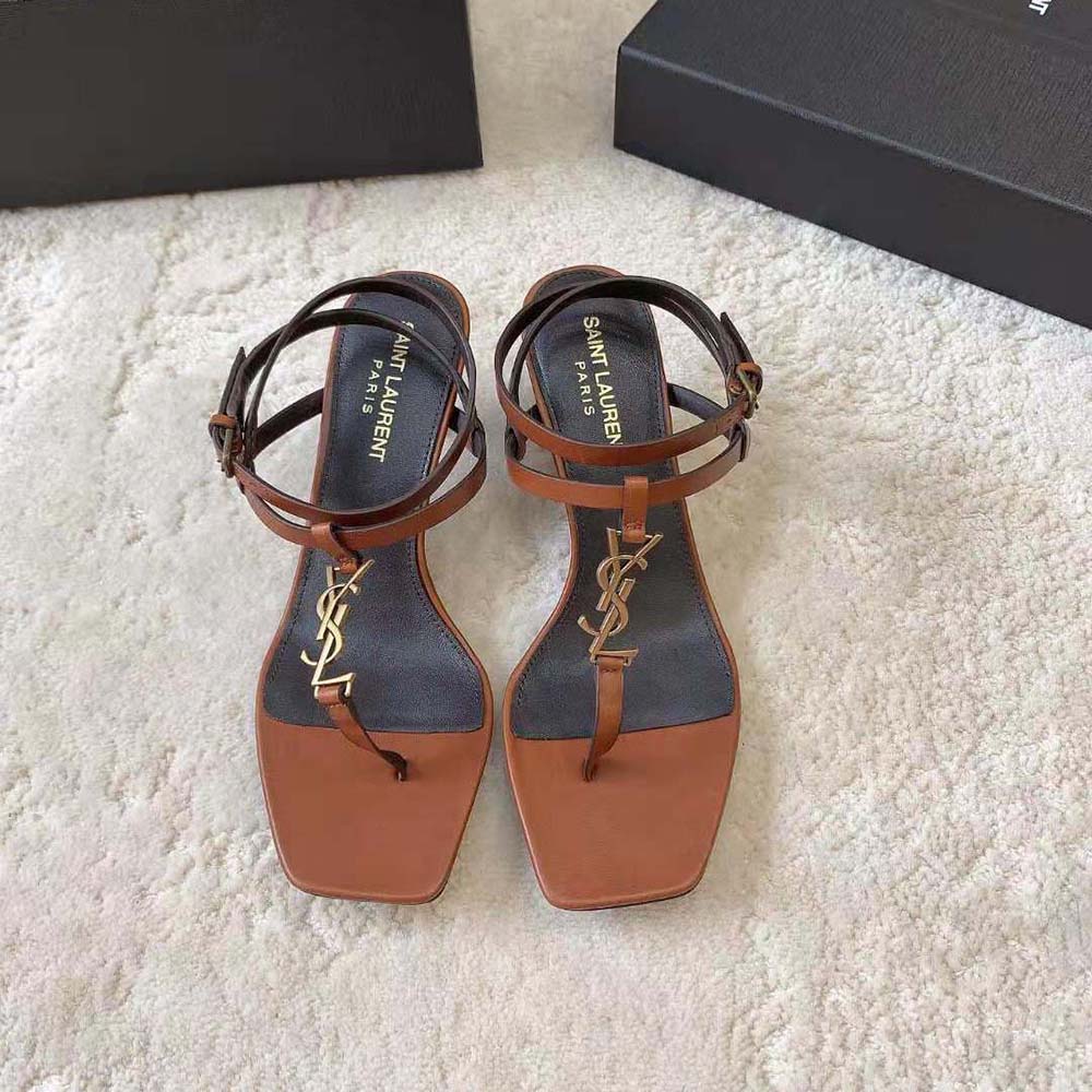Close-up of gold YSL logo detail on Cassandra Sandals in brown leather