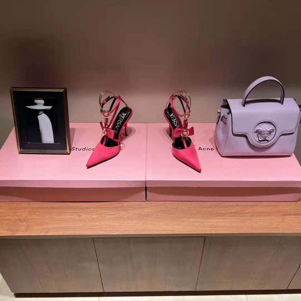 Close-up of rose satin and gold Versace hardware on ribbon cage pumps