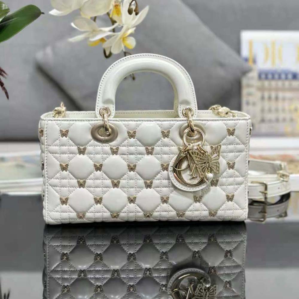 Close-up of gold-finish butterfly studs on Dior Medium Lady D-joy Bag white leather