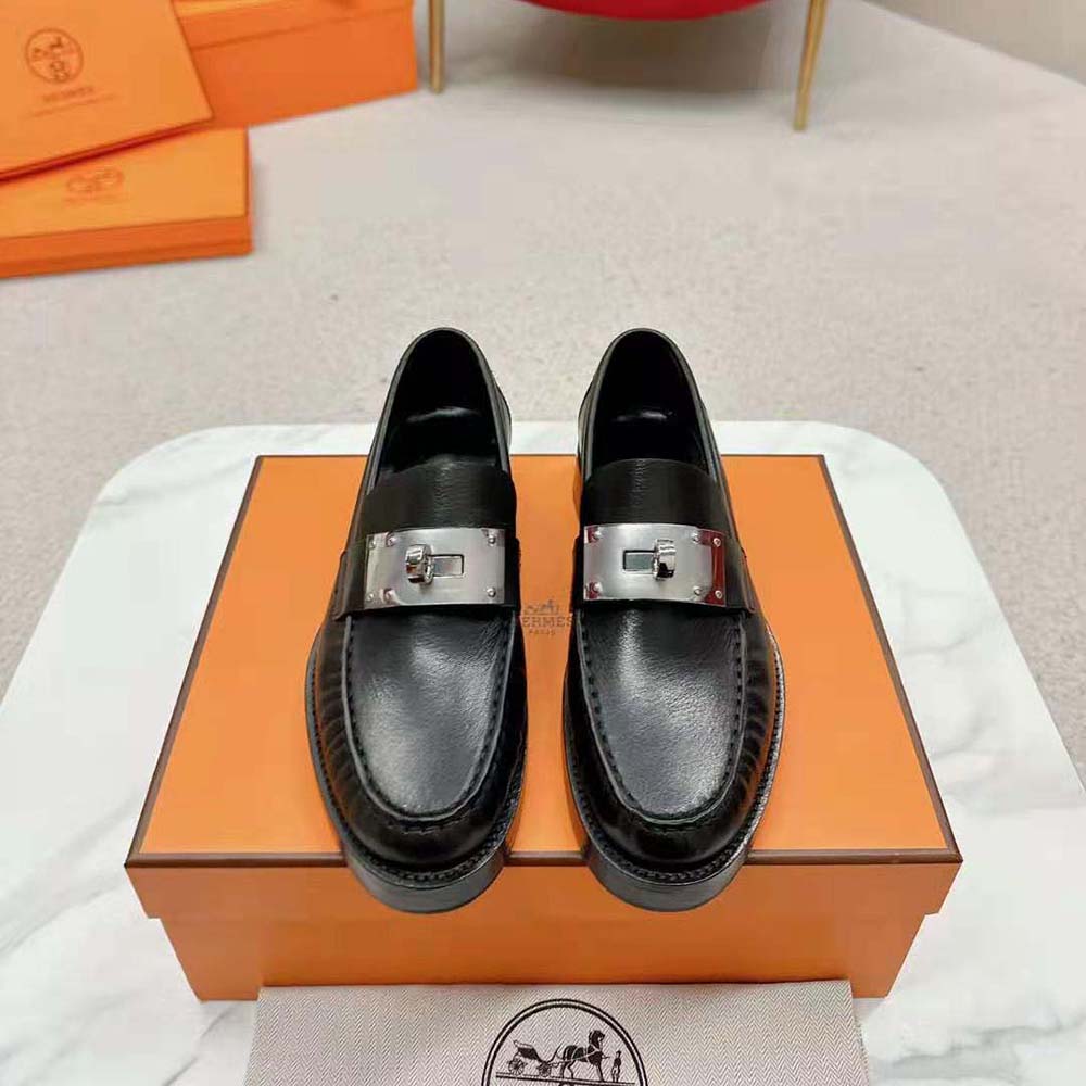 Close-up of silver-tone hardware and smooth black calfskin on Hermes loafer