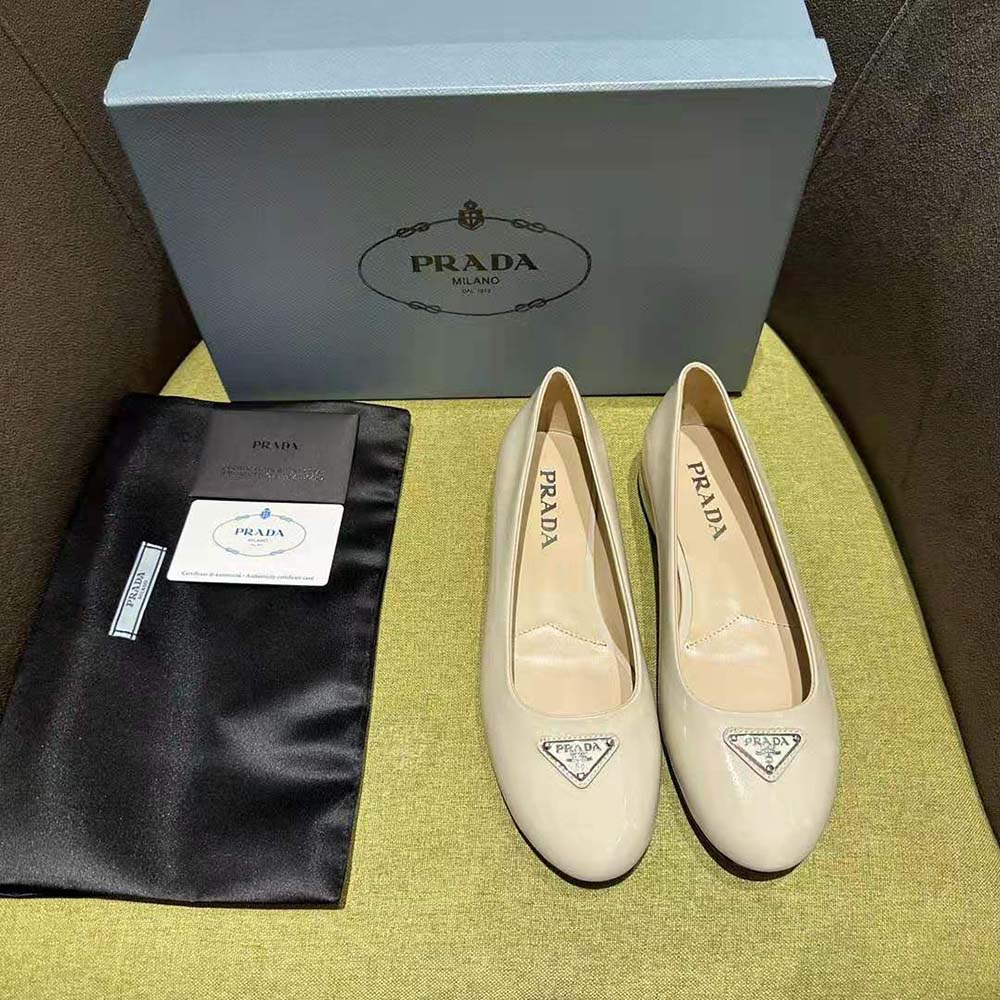 Close-up on embossed Prada logo detail on white patent ballerinas