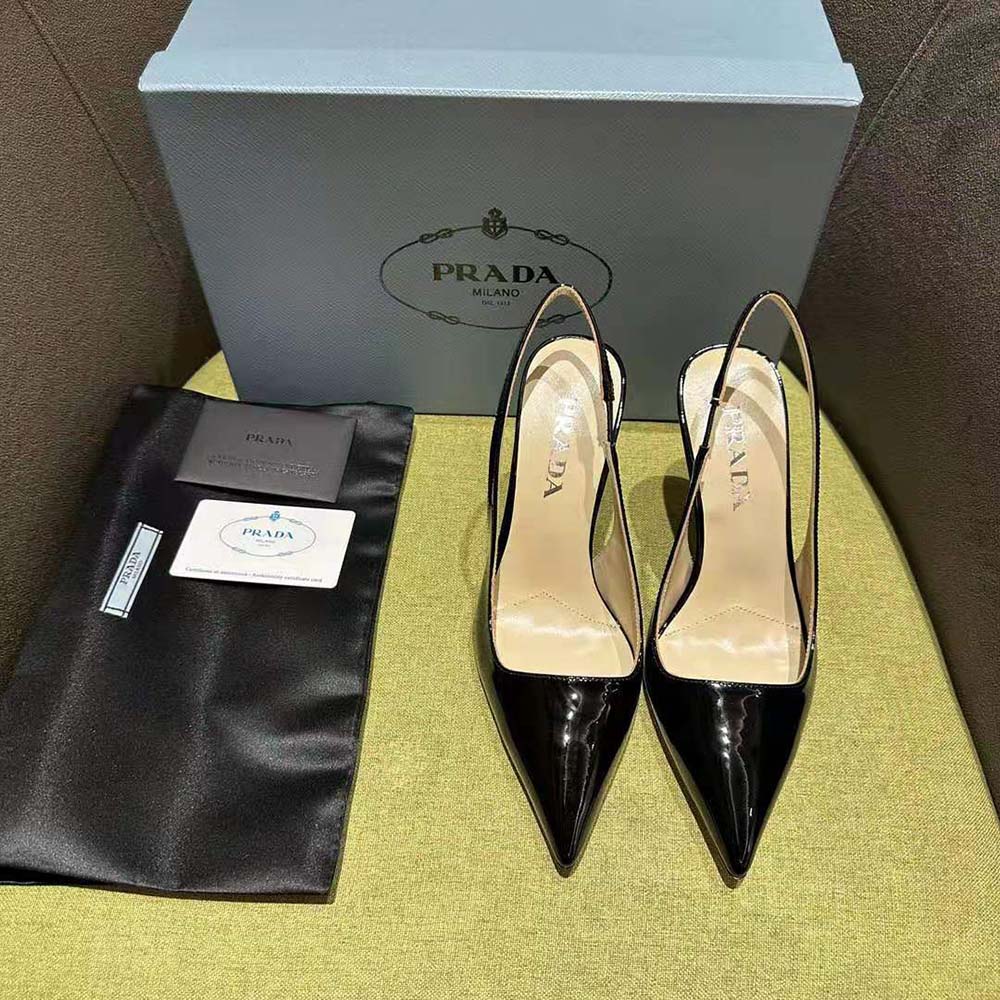 Close-up on signature Prada metal logo on black patent leather slingbacks