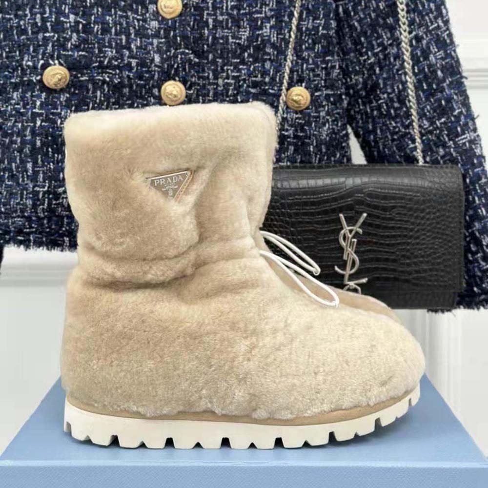 Close-up of enameled metal triangle logo on Prada Women Shearling Booties beige