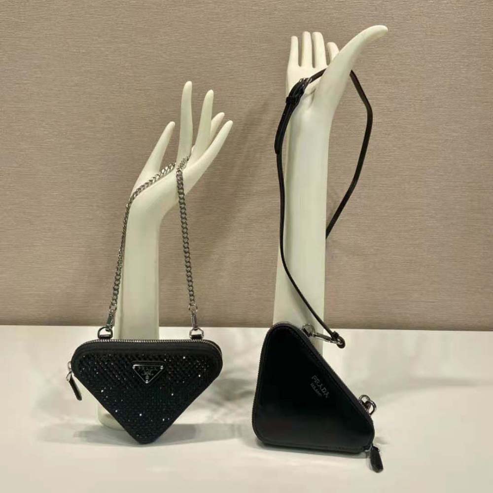 Close-up of Prada signature triangular silver embellishment on black mini-pouch