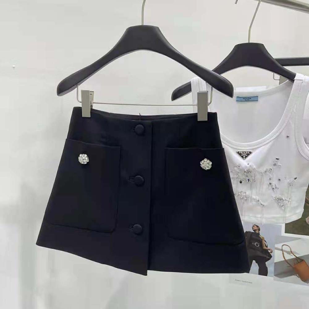 Close-up of Prada logo hardware on black wool satin miniskirt