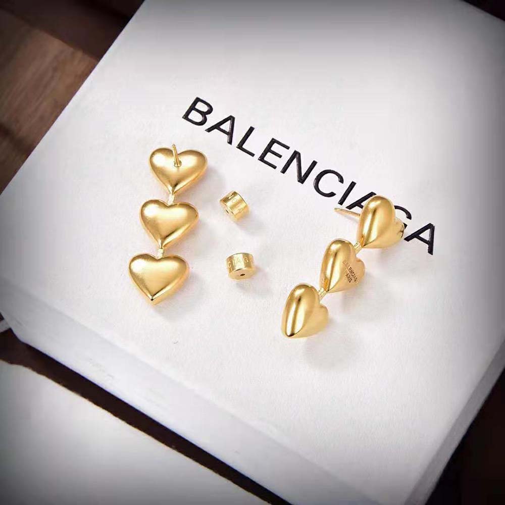 Styled shot of Balenciaga Women Heart Earrings catching light on gold brass
