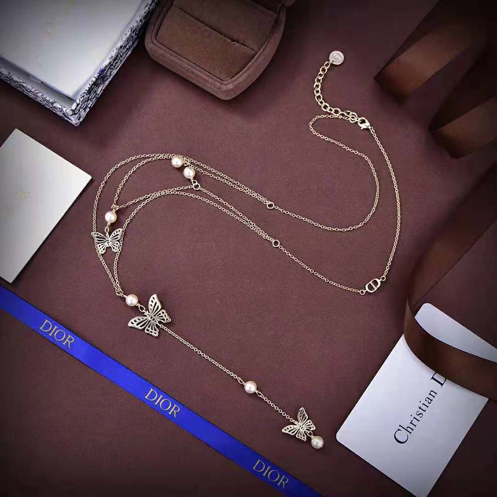 Side angle highlighting gold-finish metal and white resin pearls on necklace