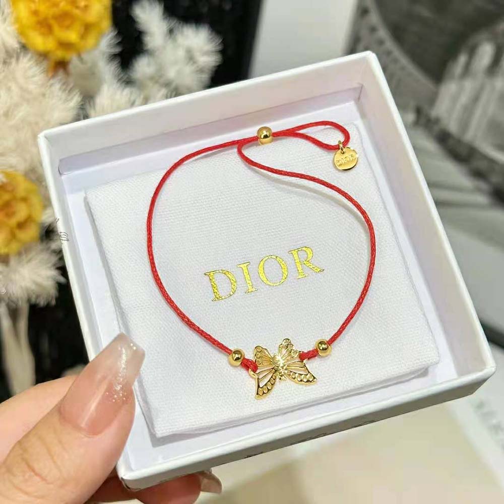 Styled shot of Dior Women Diorelita Bracelet highlighting gold hardware and vibrant red
