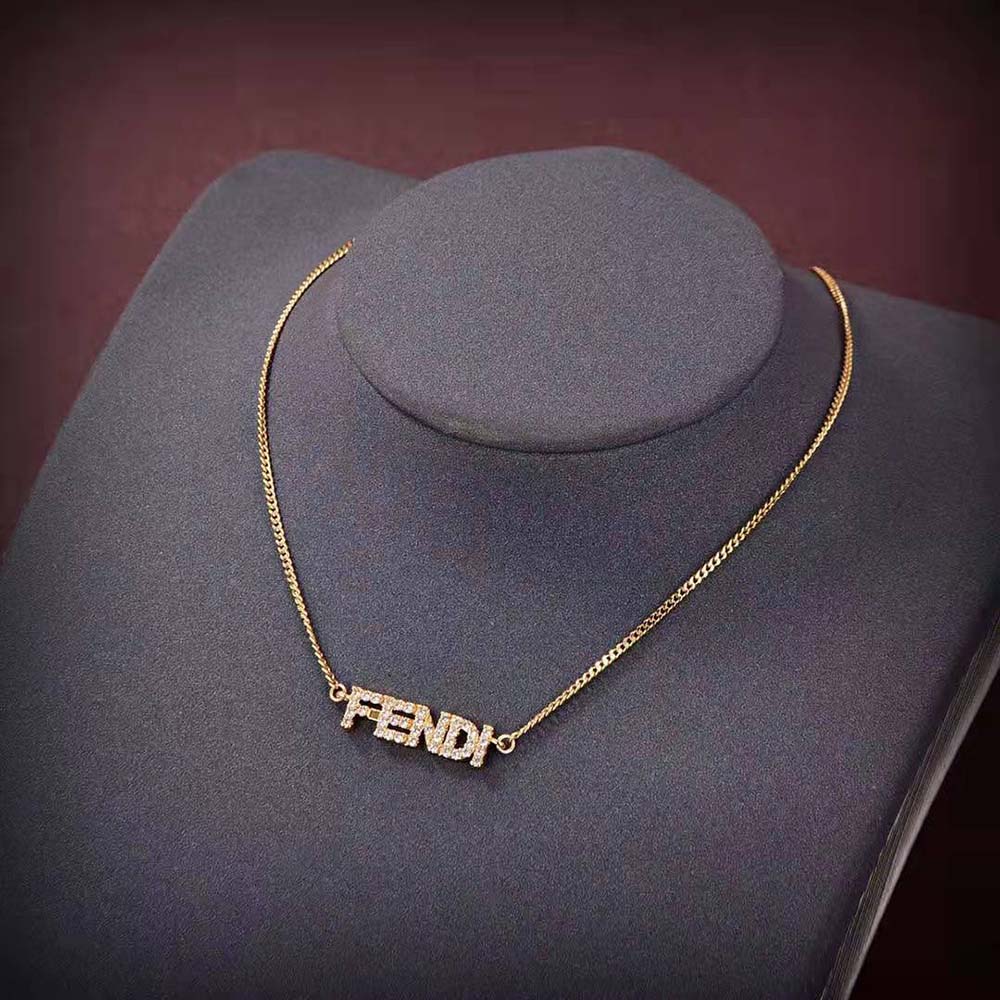 Close-up of embossed Fendi logo detail on gold-colored necklace