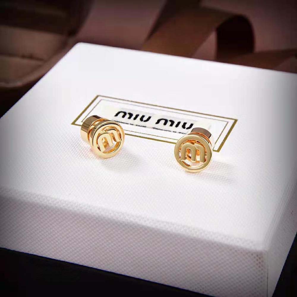 Close-up of gold metal and laser-etched Miu Miu logo on the back of earrings