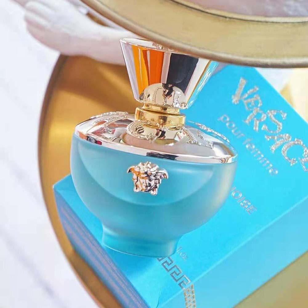 Close-up on turquoise glass and Medusa emblem of Versace Women Dylan Turquoise Edt 100 ml