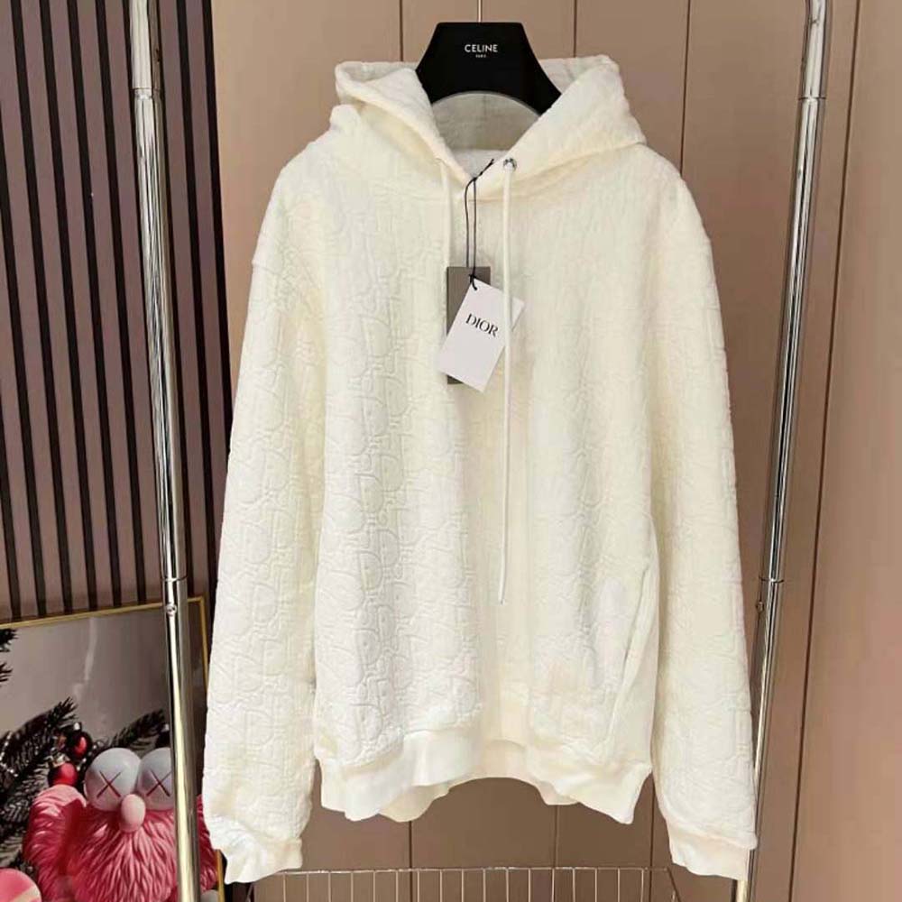 Close-up detail of Dior Oblique signature on white hooded sweatshirt