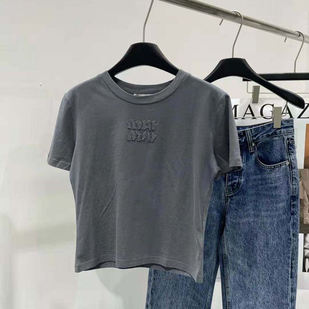 Close-up detail of embroidered Miu Miu logo on gray garment-dyed jersey T-shirt