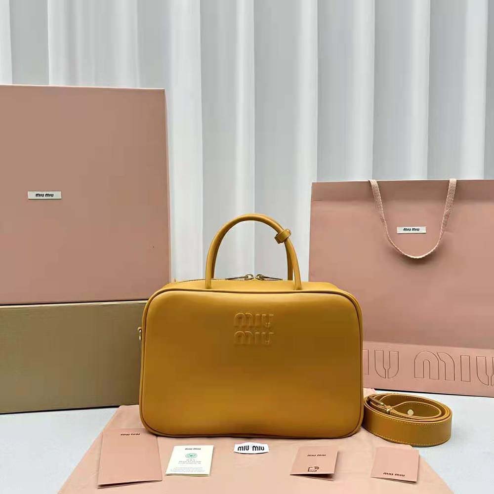Close-up of embossed lettering and gold-tone hardware on Miu Miu orange bag