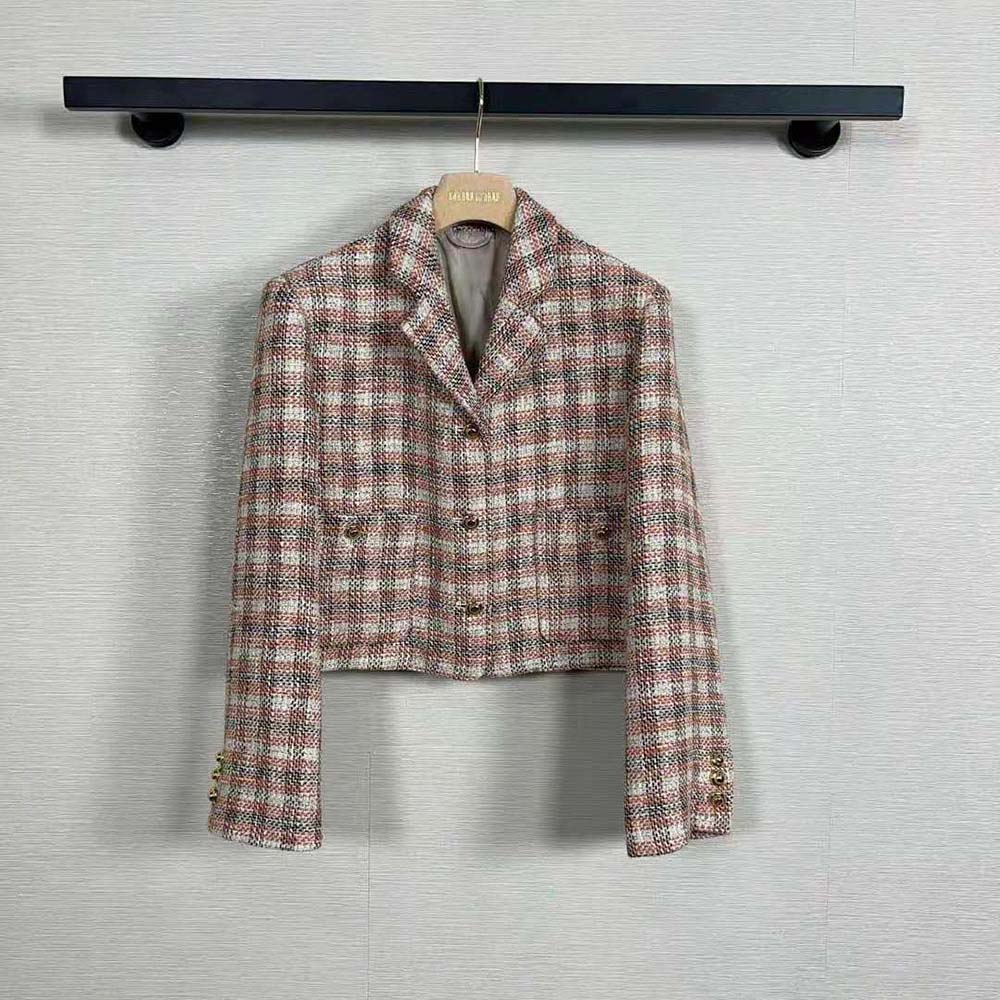 Close-up of embroidered Miu Miu logo on pink check jacket
