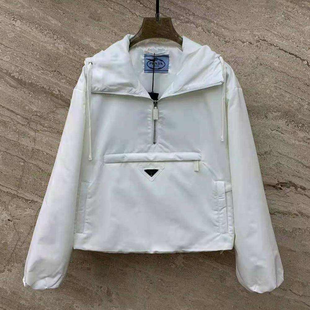 Close-up of enameled metal triangle logo on white Prada jacket