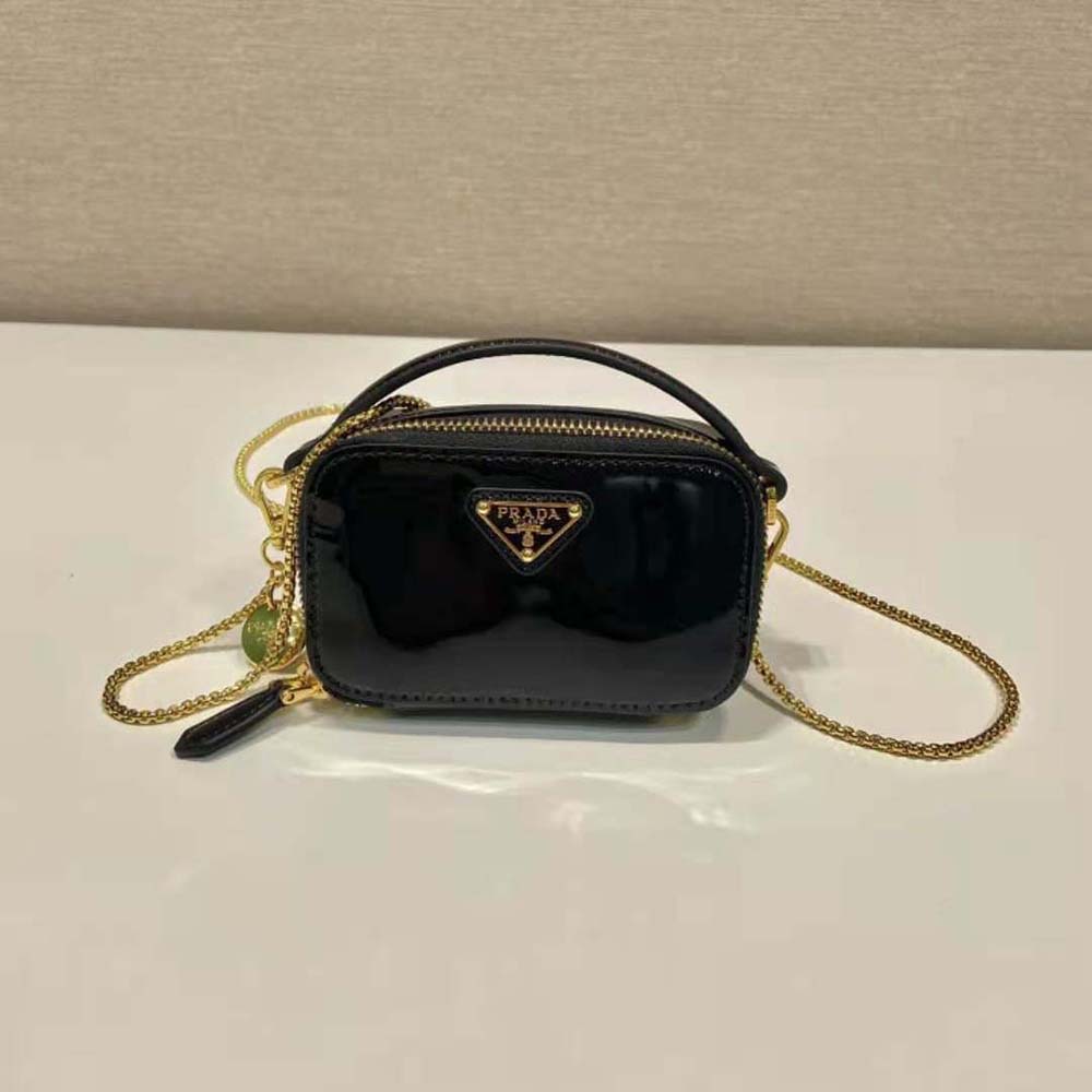 Close-up of Prada logo hardware on mini-pouch in black patent leather