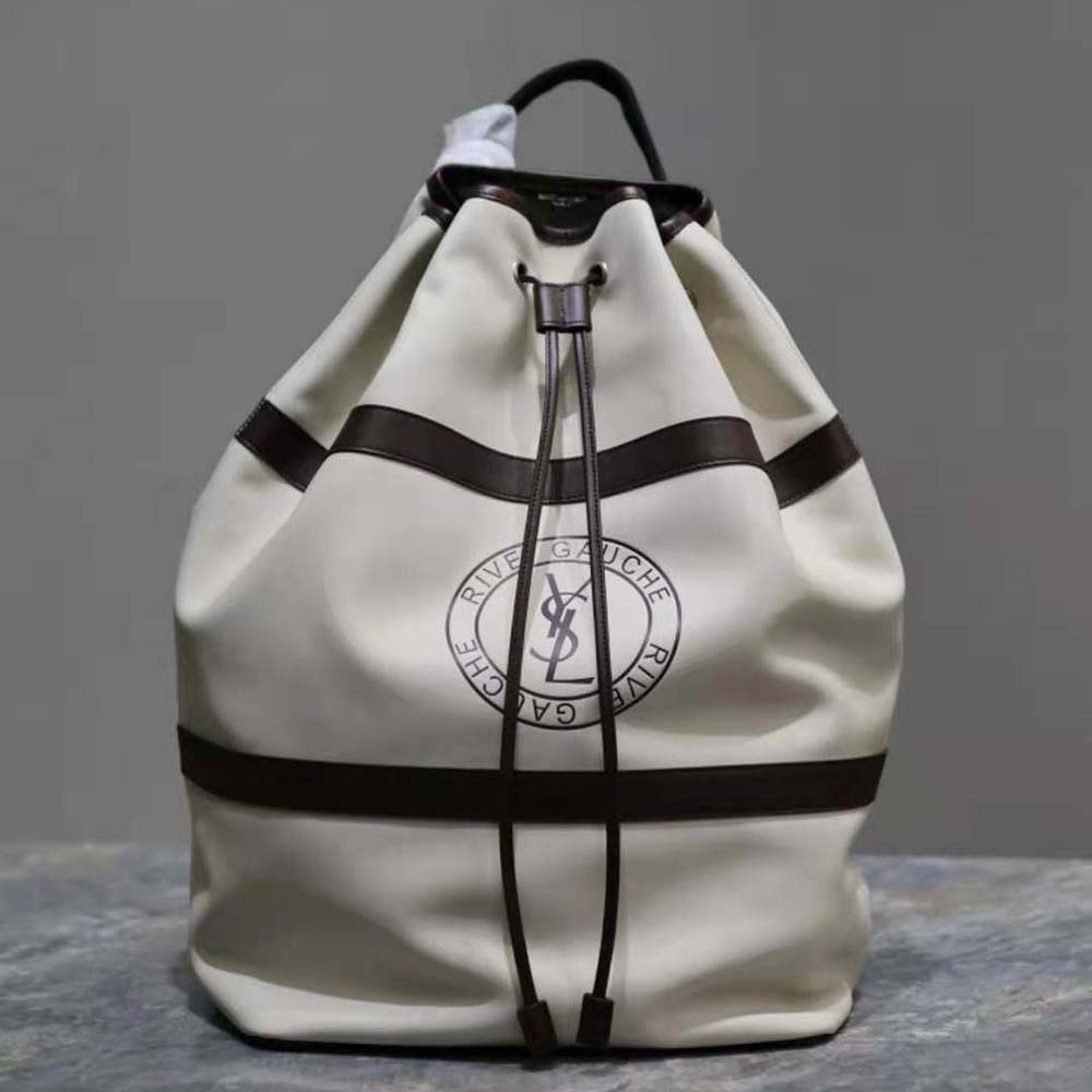 Close-up of gold YSL monogram on smooth white leather sling bag