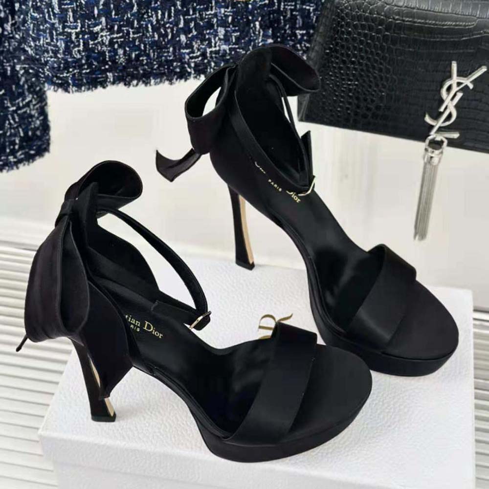 Close-up of black satin straps and silver Dior buckle on heeled sandal