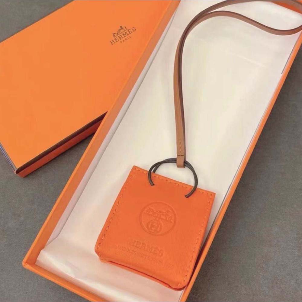 Side view of Hermes Orange Bag Charm clasp and polished metal detail