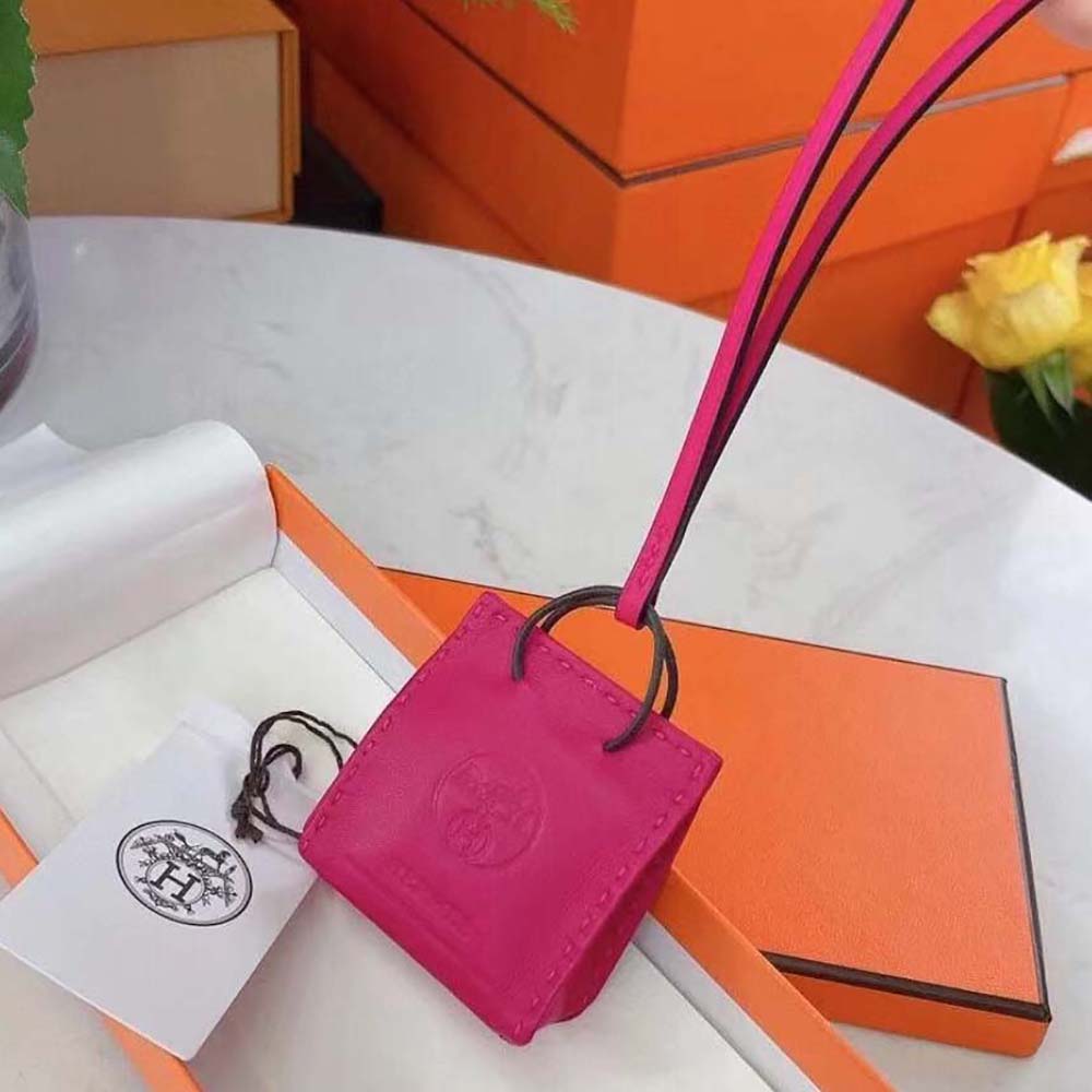Hermes Pink Bag Charm clipped onto a tote bag handle in natural light