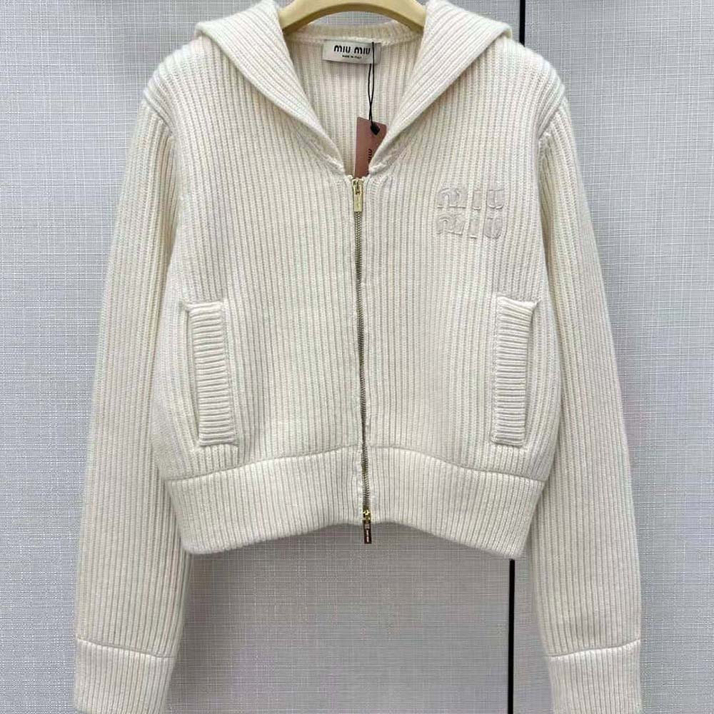Close-up of Miu Miu signature buttons on white knit cardigan