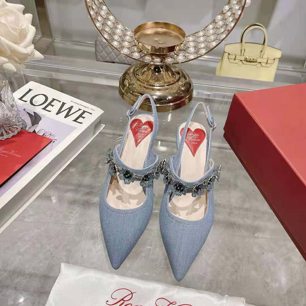 Close-up on signature Virgule flower buckle on denim slingbacks