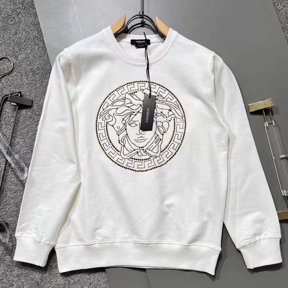 Close-up detail of sliced Medusa embroidery on Versace white sweatshirt