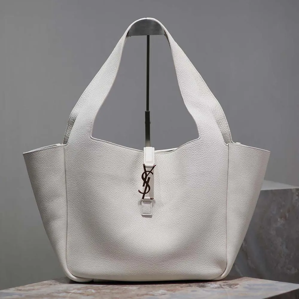 Close-up of gold YSL logo hardware on white leather bag