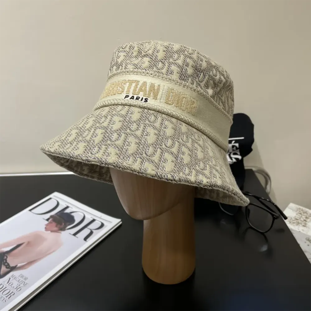 Close-up detail of gold-tone Dior Oblique embroidery on white bucket hat