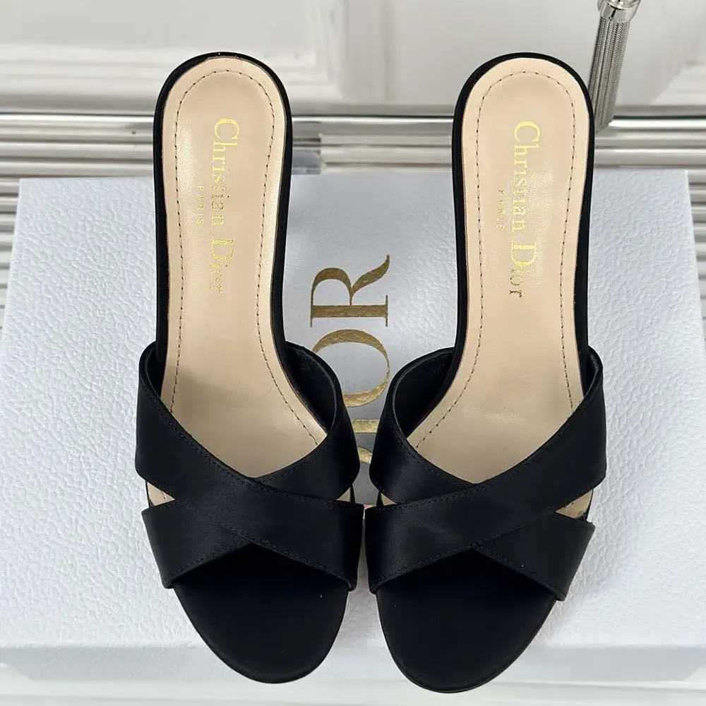 Close-up of gold-tone Dior Tribales stud on black satin slide