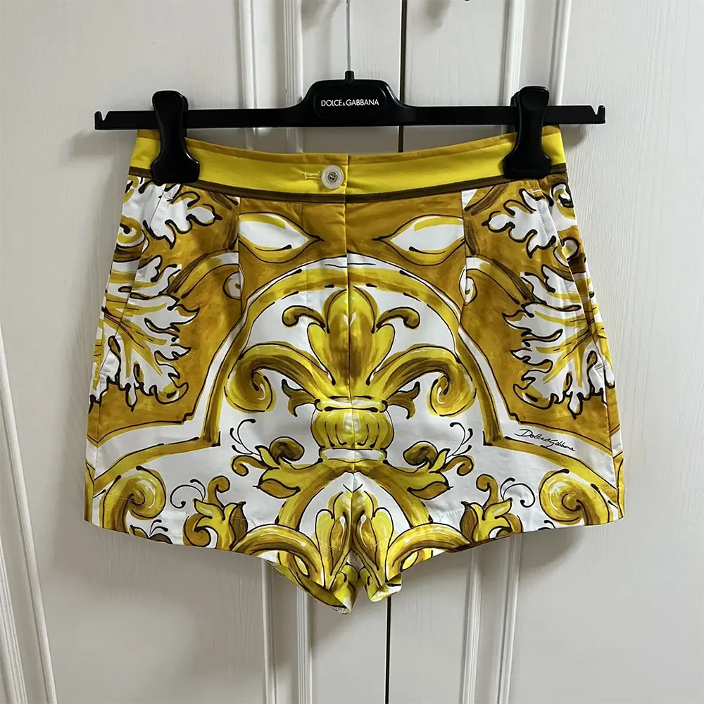 Close-up of Majolica print and branded button on yellow shorts