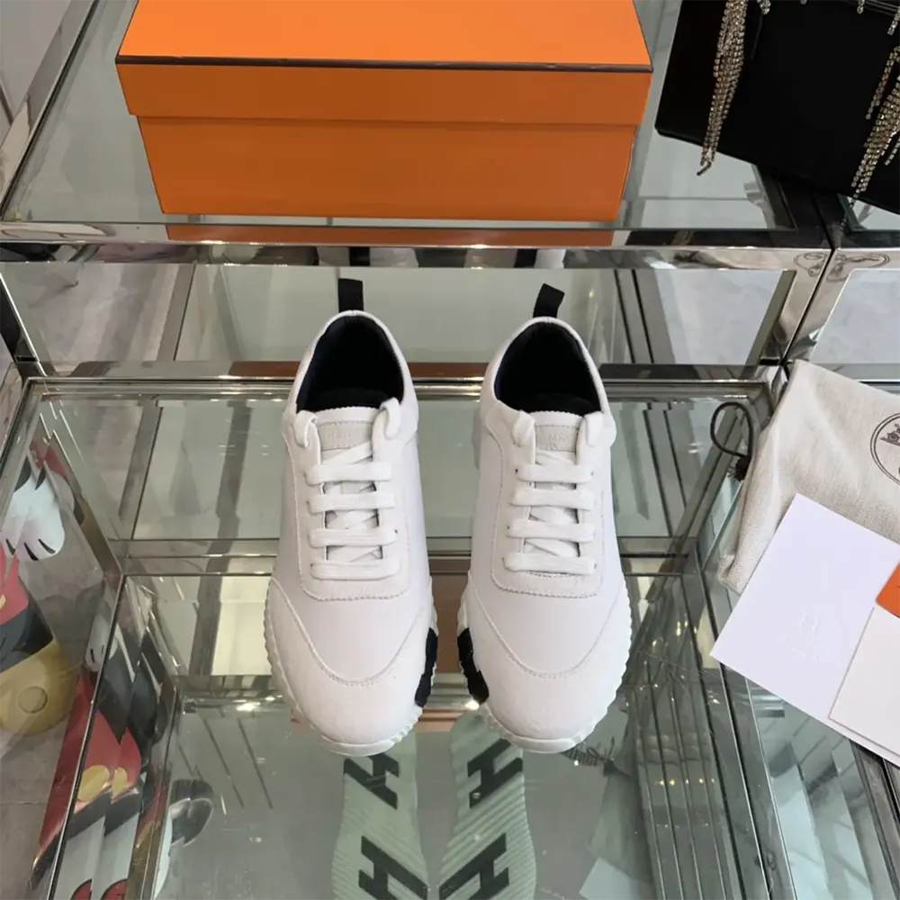 Close-up of embossed Hermes logo on white leather sneaker