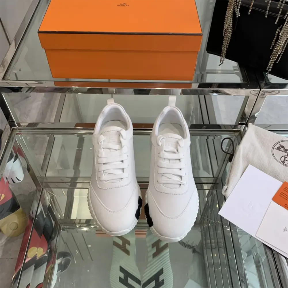 Close-up of Hermes embossed hardware on white leather sneaker