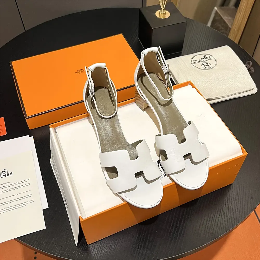 Close-up of white leather and signature hardware on Hermes Women Encens 50 Sandal-White